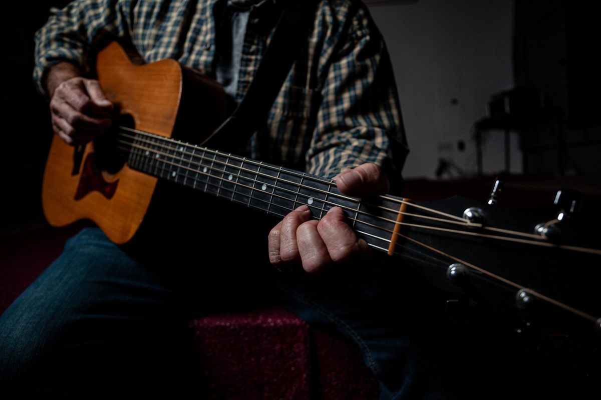 Close-up of a hand fretting a chord on an acoustic guitar
