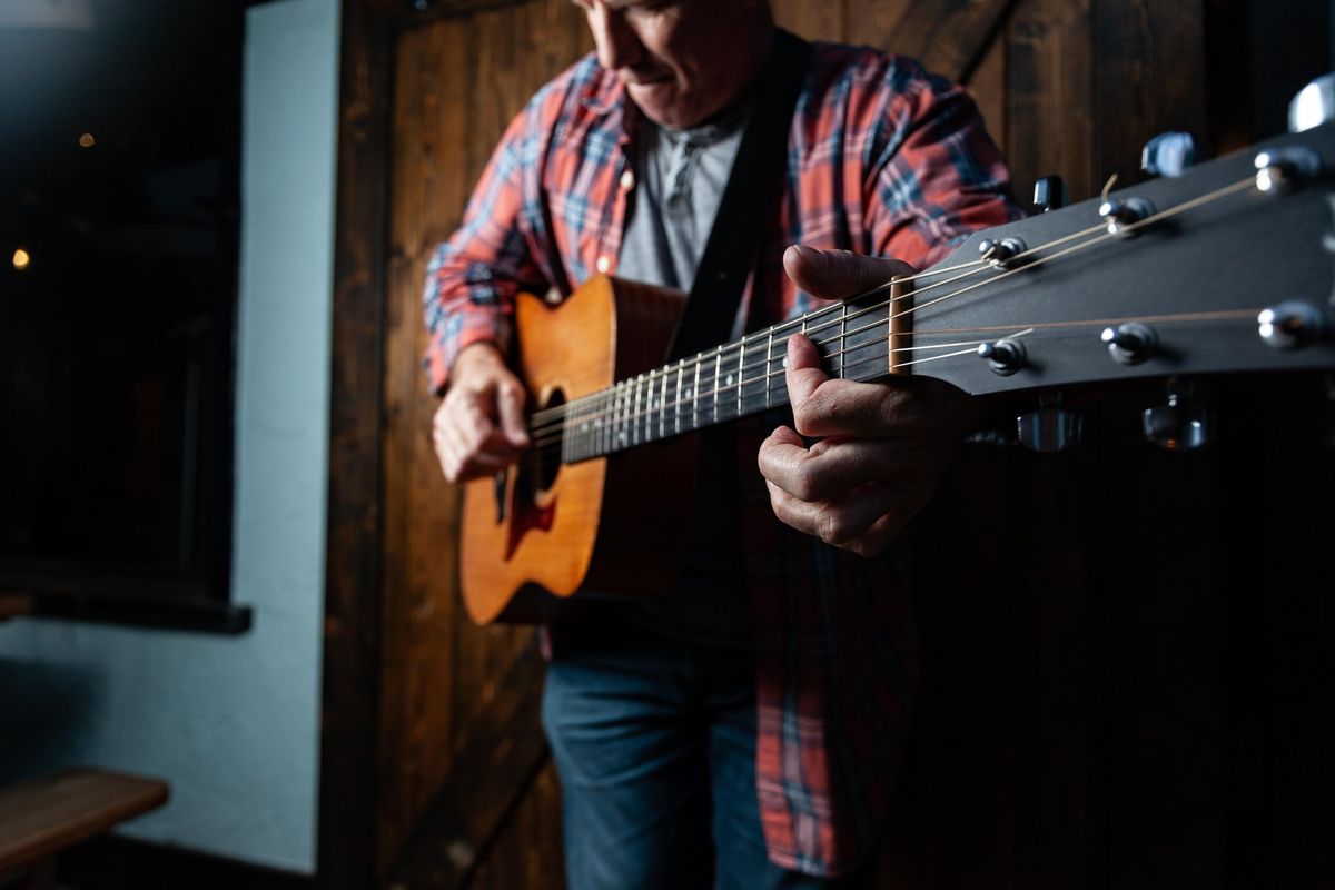 Catfish Jack playing acoustic guitar, fretting hand up the neck